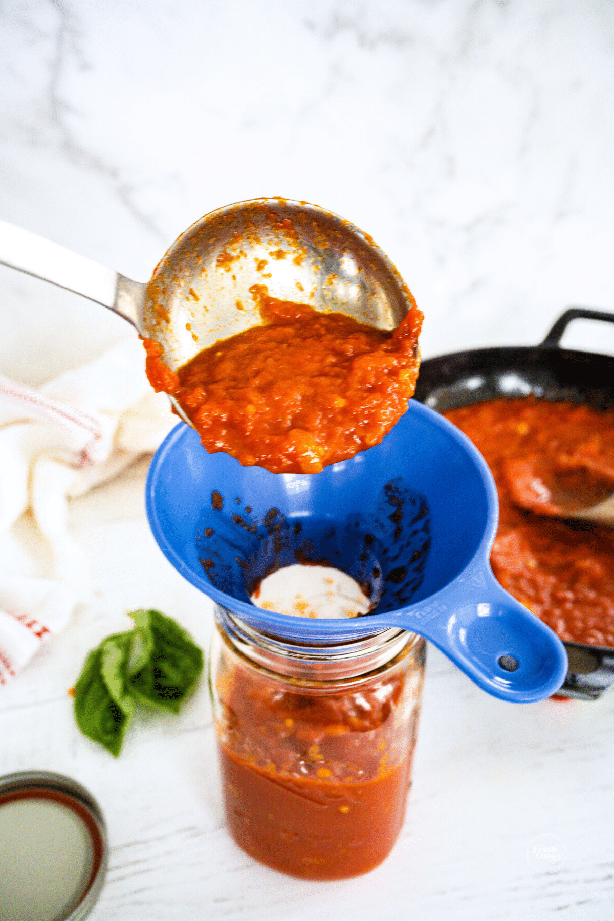 Ladling marinara sauce into a jar.