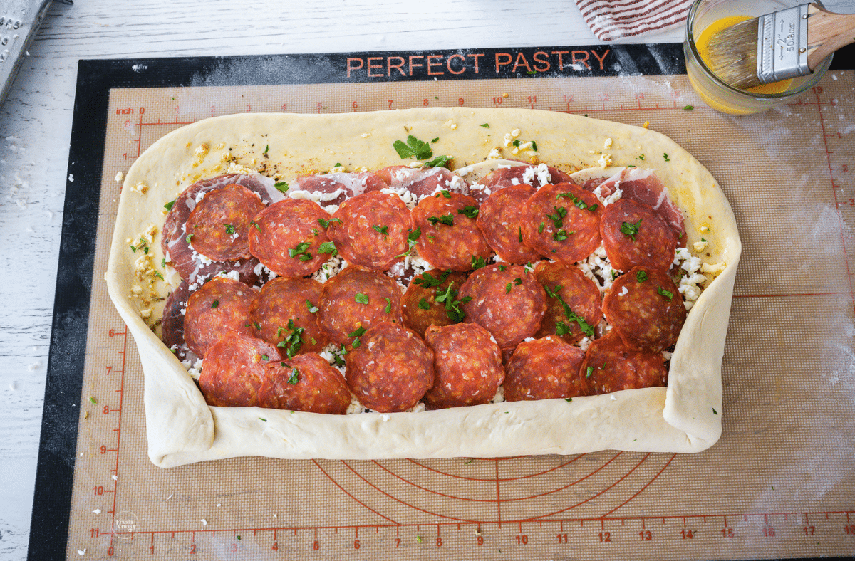 Start rolling stromboli from long edge, tucking sides in like a burrito. 