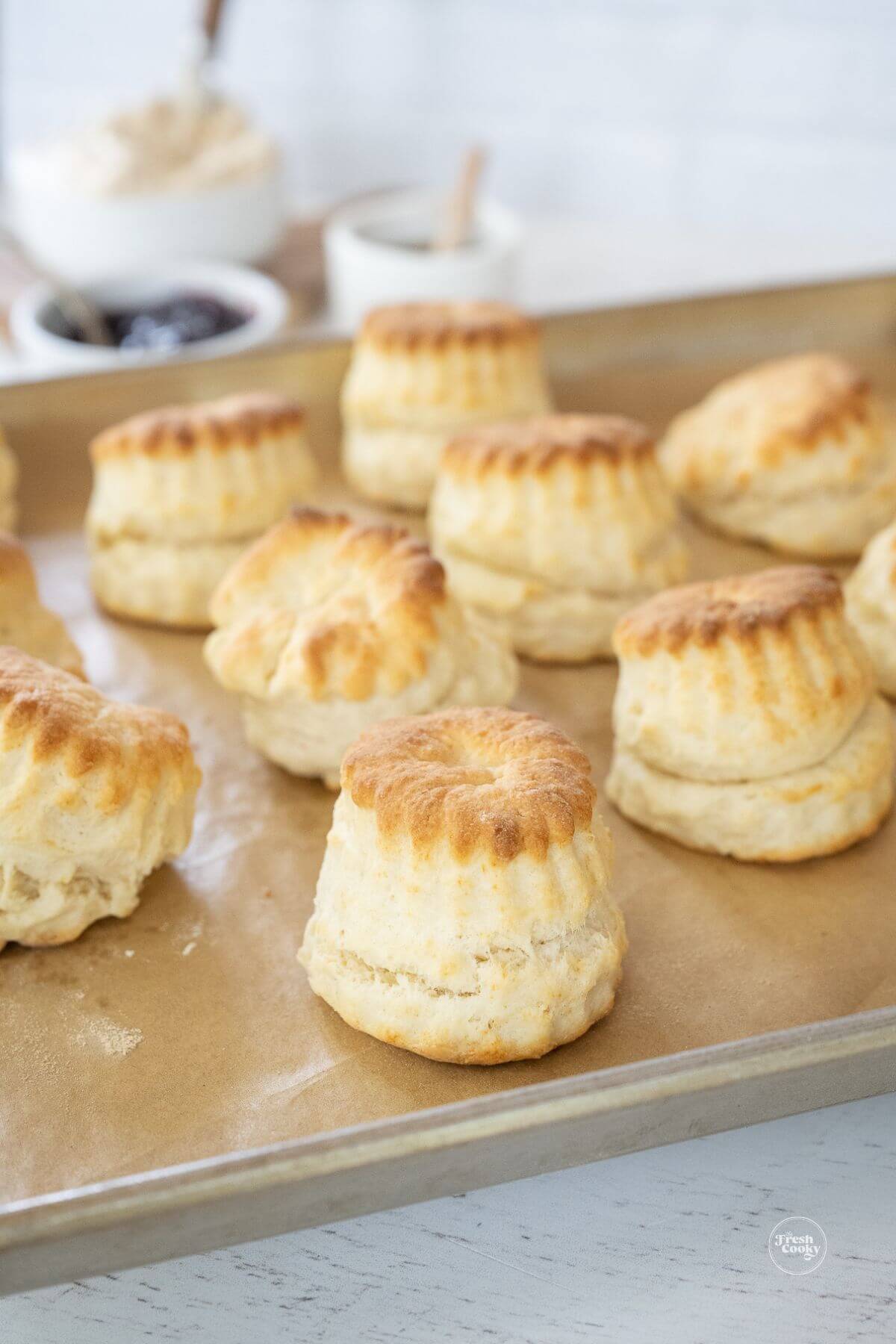 Puffed, tall, flaky and tender biscuits on baking sheet.