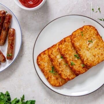 Air Fryer Hash Brown Patties with air fried sausage links nearby and some ketchup for dipping.