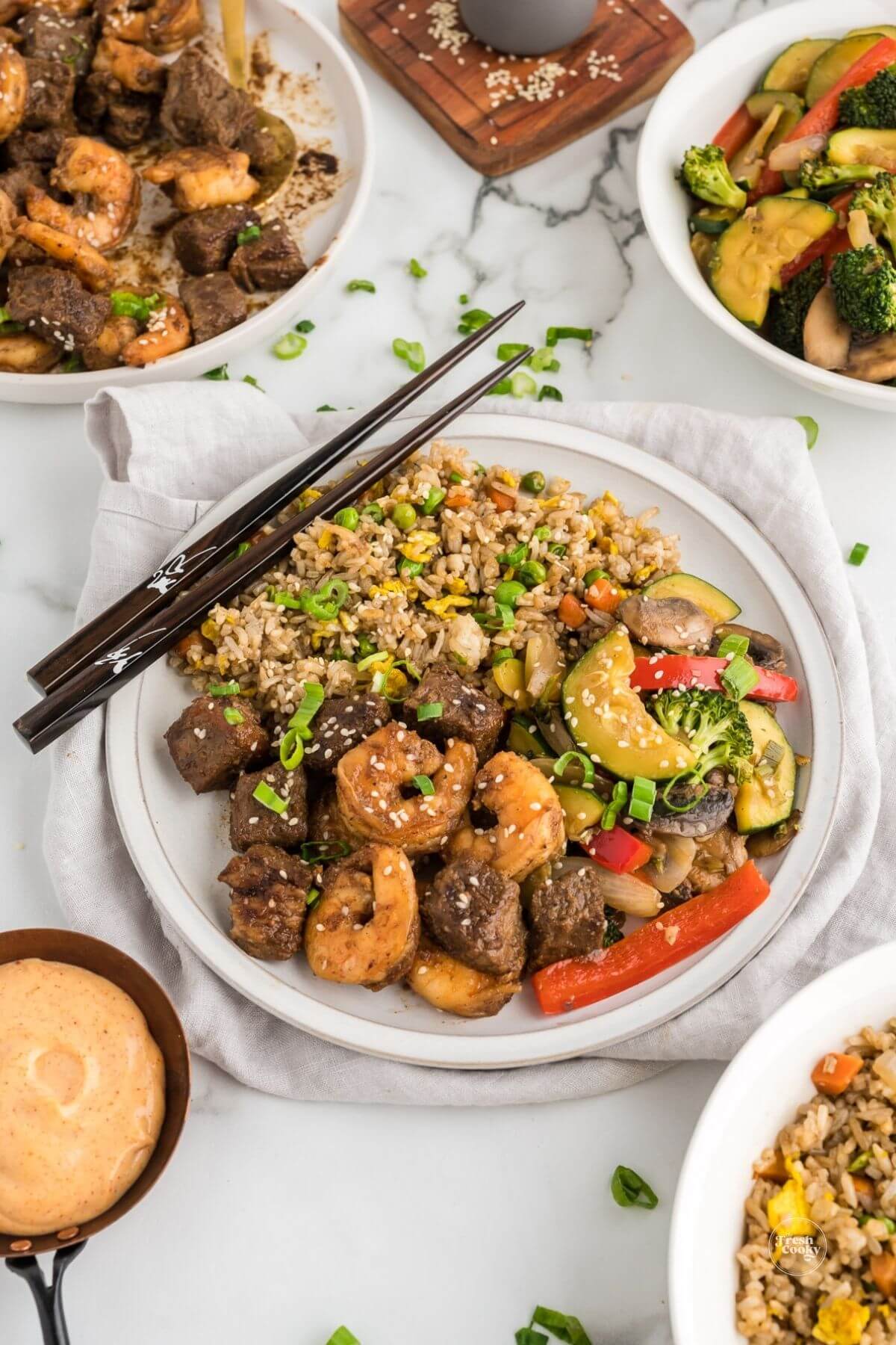Hibachi steak and shrimp with hibachi vegetables and fried rice with chopsticks.