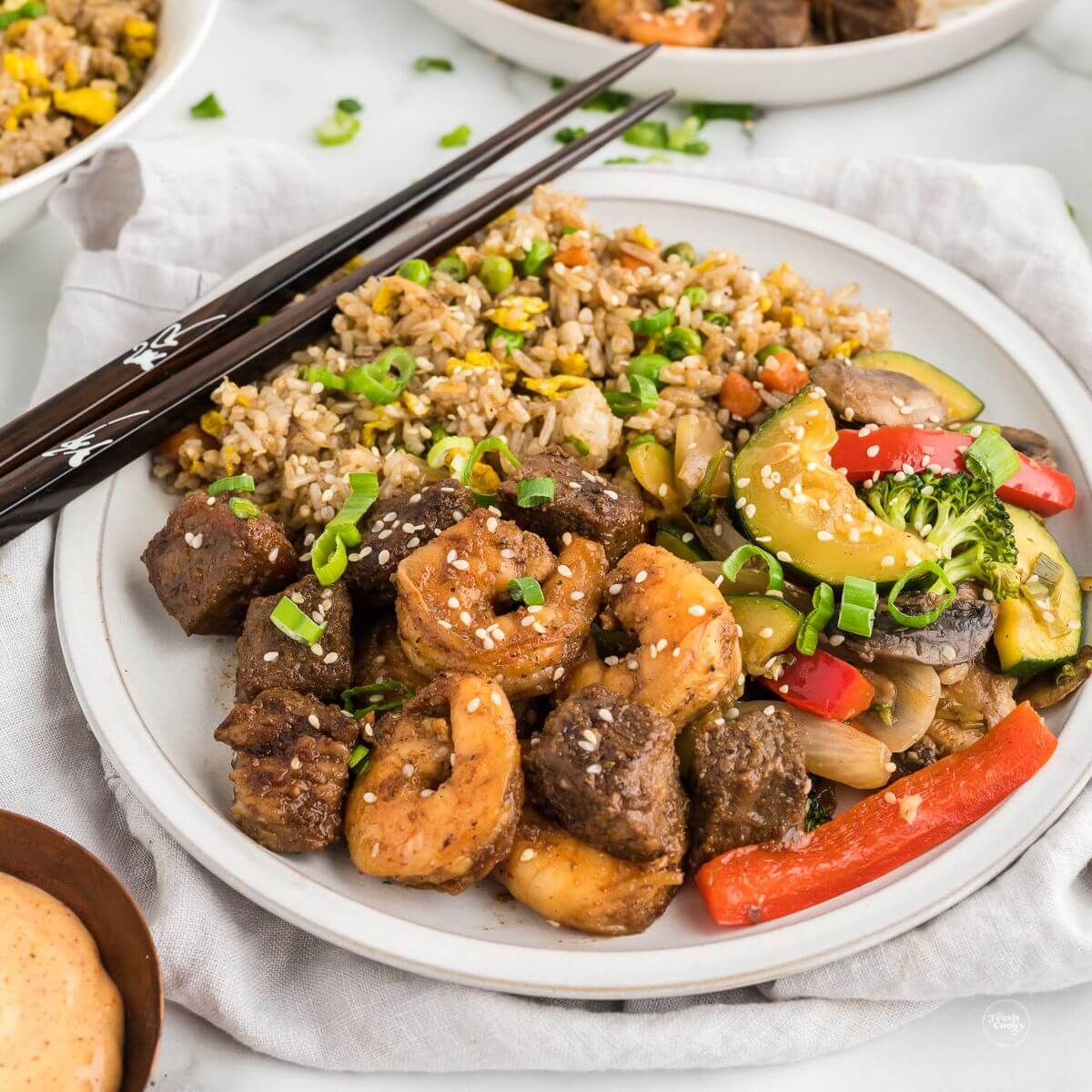 Plate of hibachi steak and shrimp with chopsticks and hibachi vegetables and fried rice.