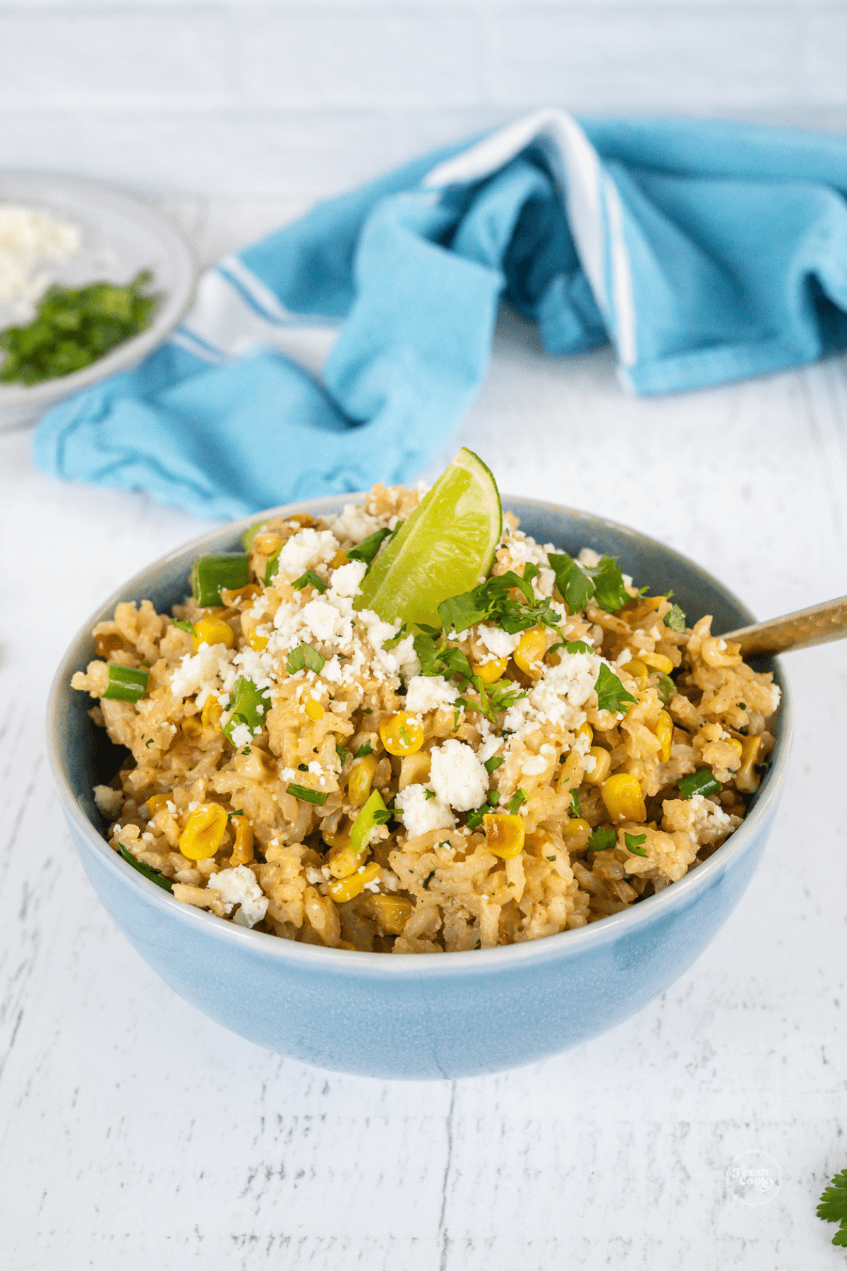 Bowl filled with easy Mexican rice and roasted corn, topped with cotjia cheese, lime and cilantro.