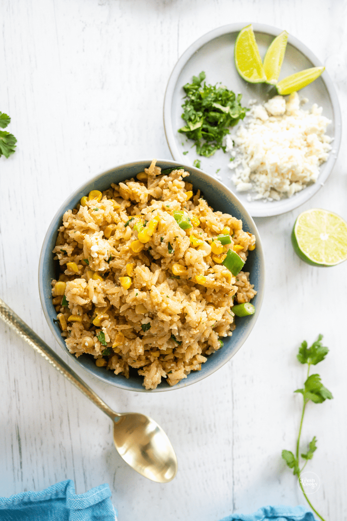 Mexican corn rice recipe in a bowl with toppings on a plate nearby. 