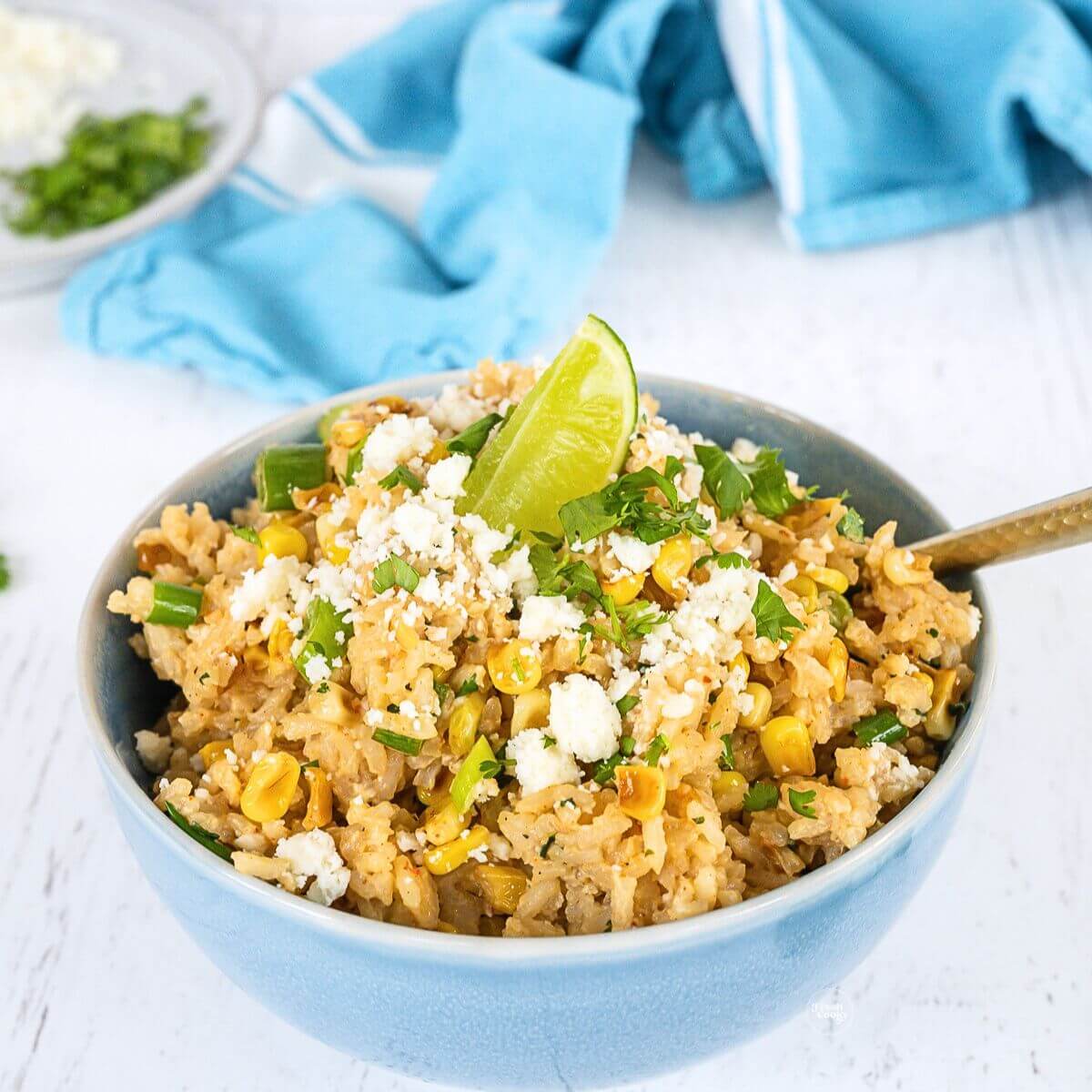 Mexican corn rice in a bowl topped with cotija cheese, and fresh lime.