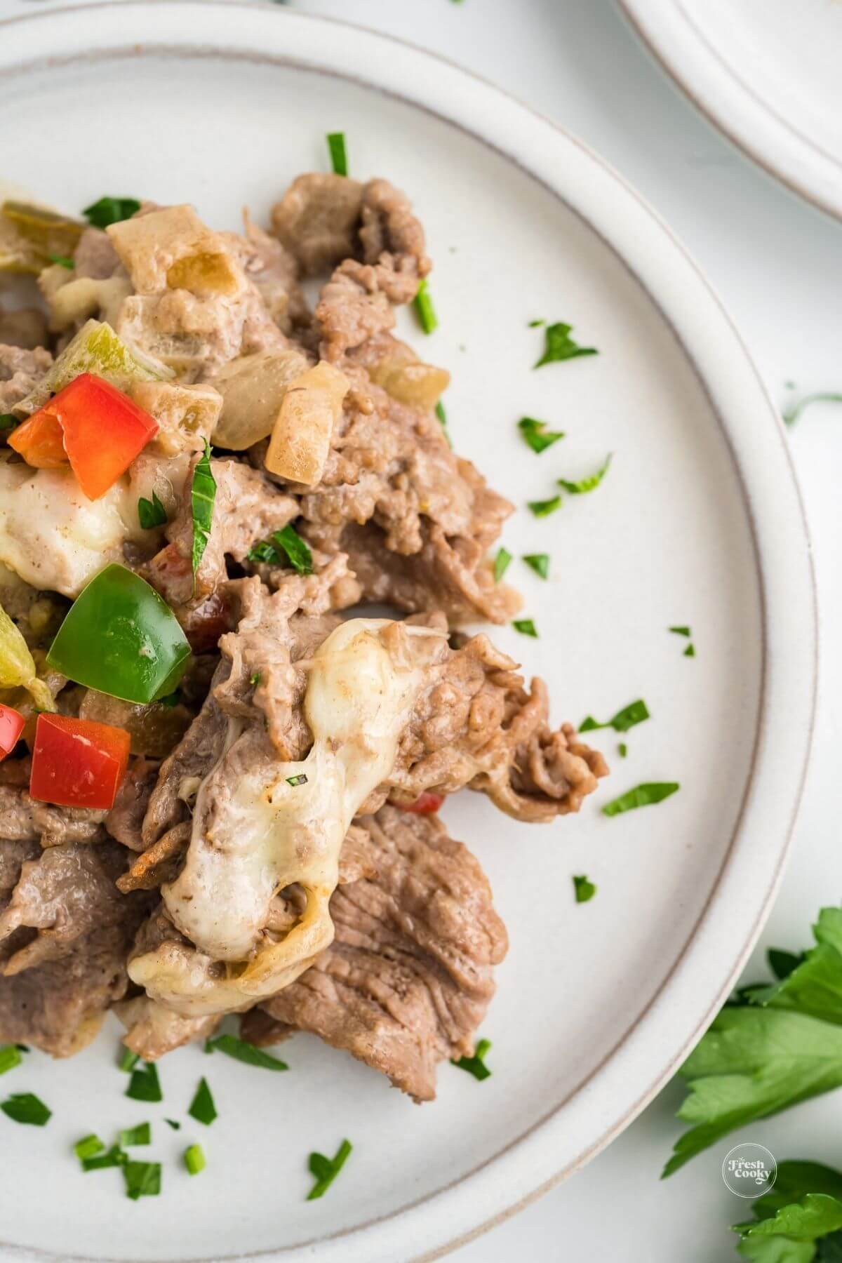 Serving of Philly cheesesteak casserole on a plate topped with fresh parsley.