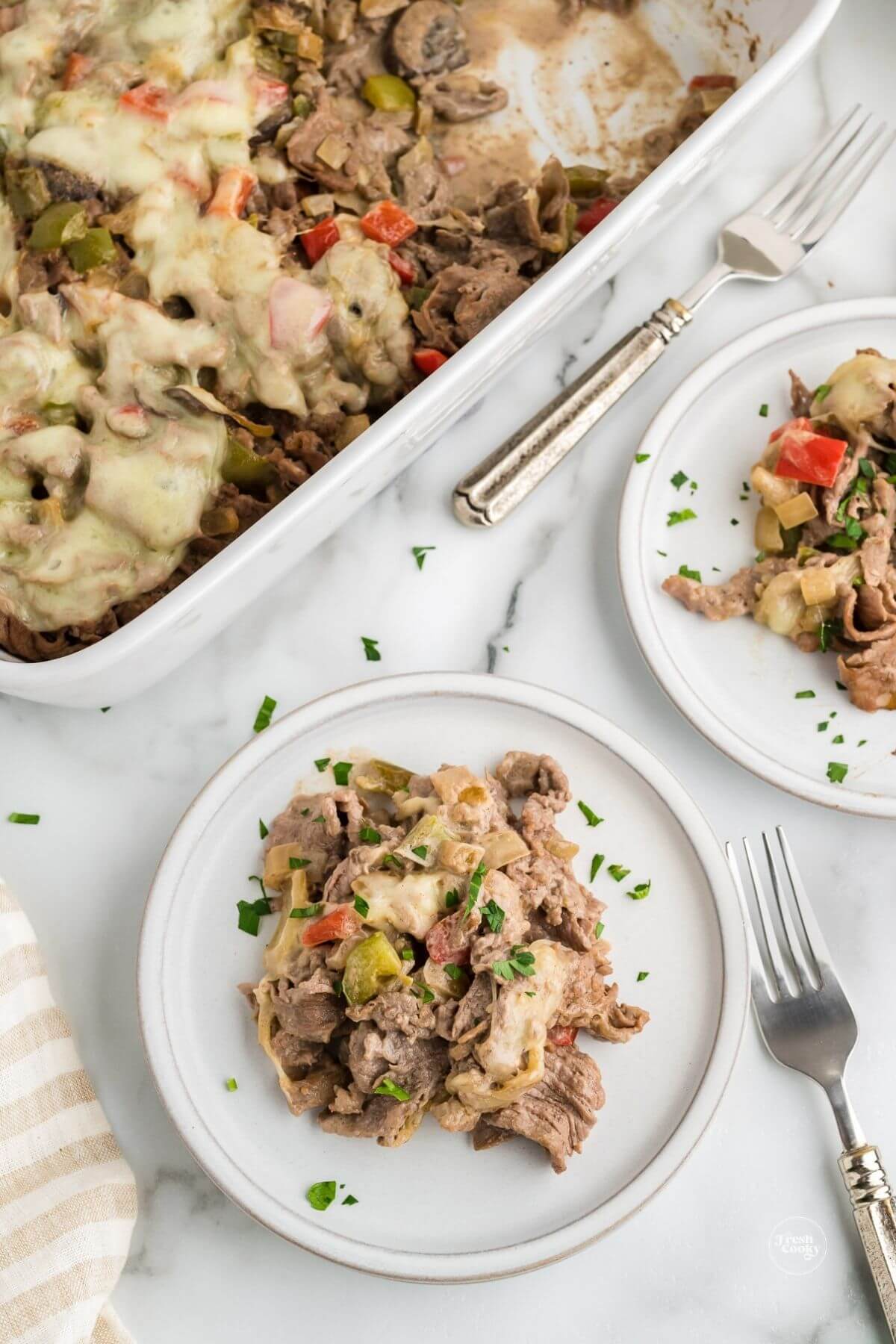 Servings of low carb Philly cheesesteak casserole on a plate with casserole dish behind.