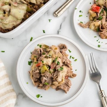 Serving of philly cheesesteak casserole on plate with casserole in background.