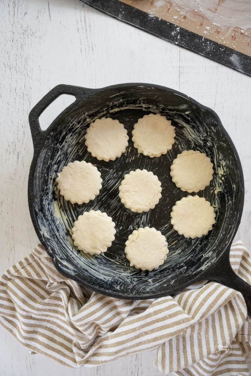 Placing biscuits in a buttered skillet.