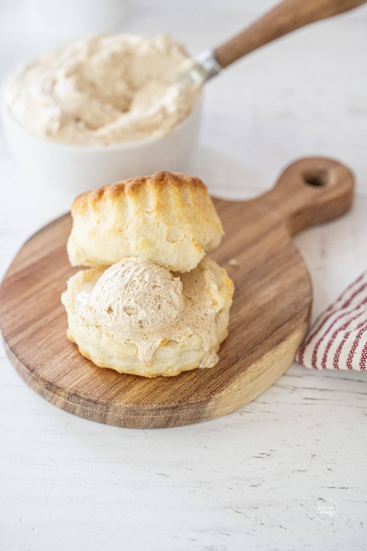 Sliced tall biscuit on cutting board with cinnamon honey butter.