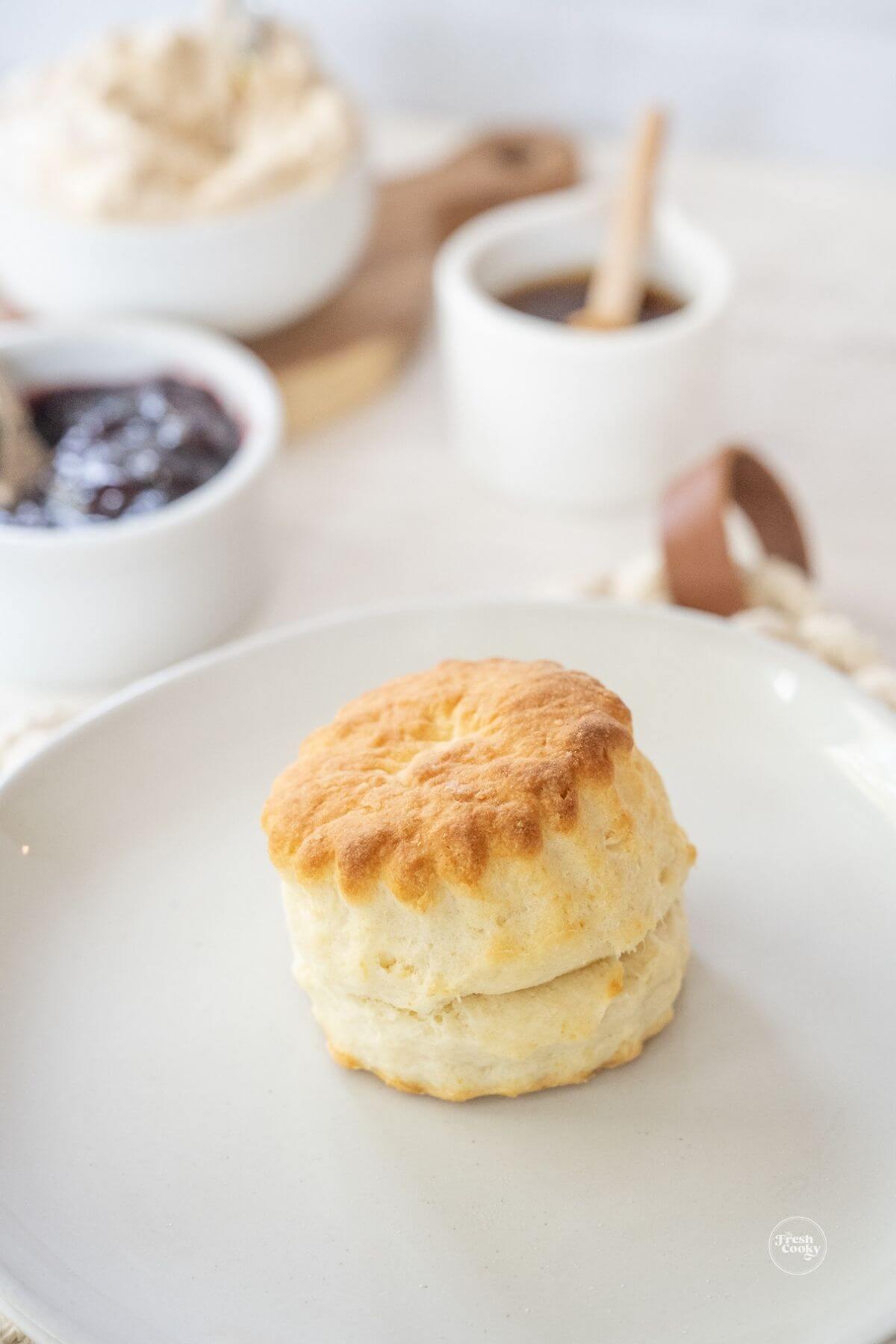 Fluffy 2 ingredient biscuit on plate with jam, honey and butter in background.