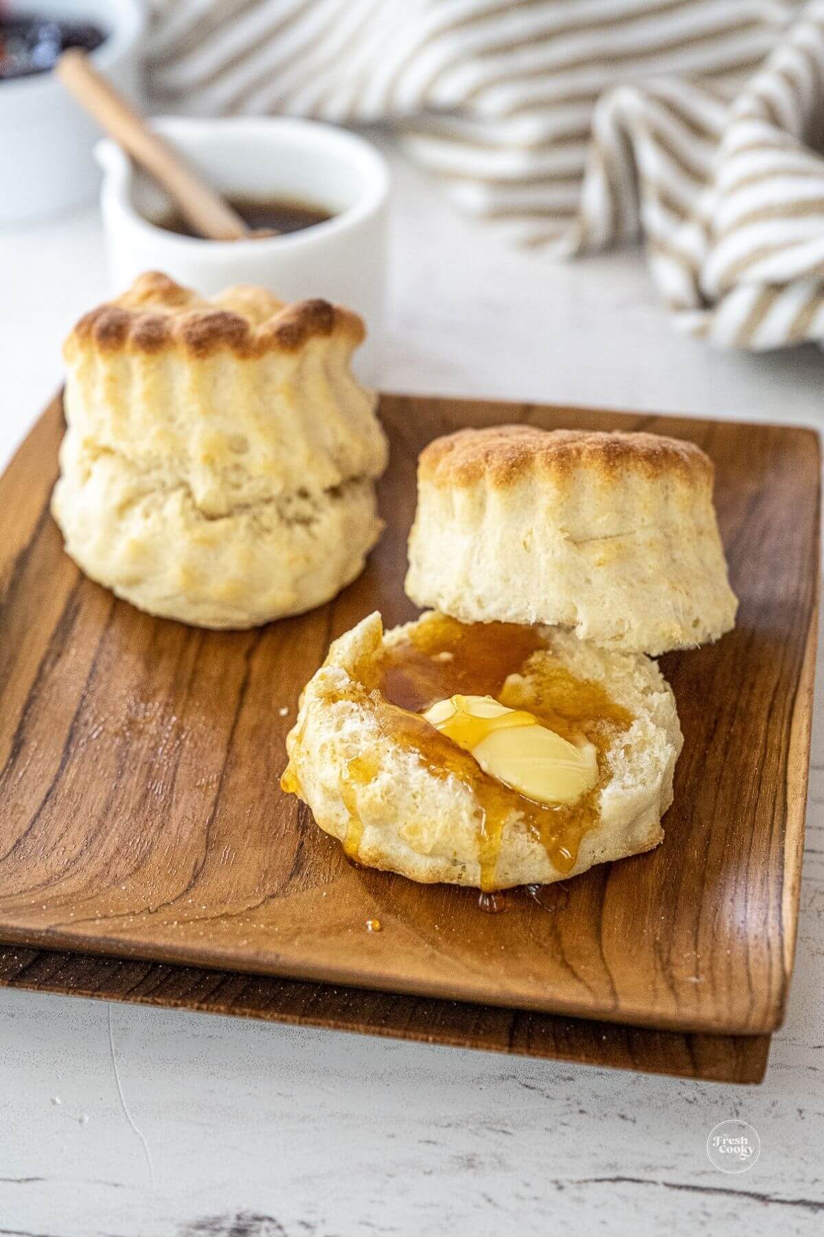 Biscuits on wooden plates, with butter and some honey.