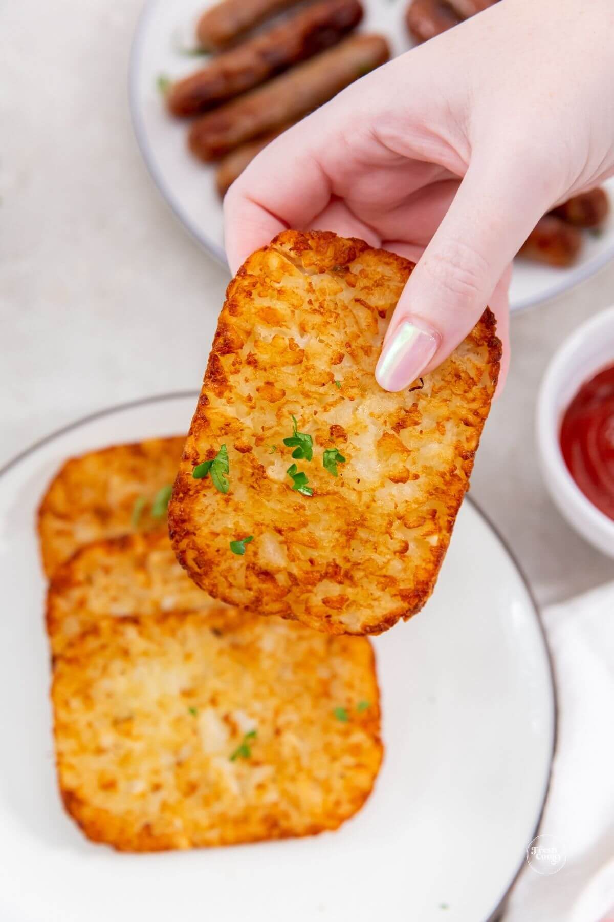 Hand holding hash brown patty. 