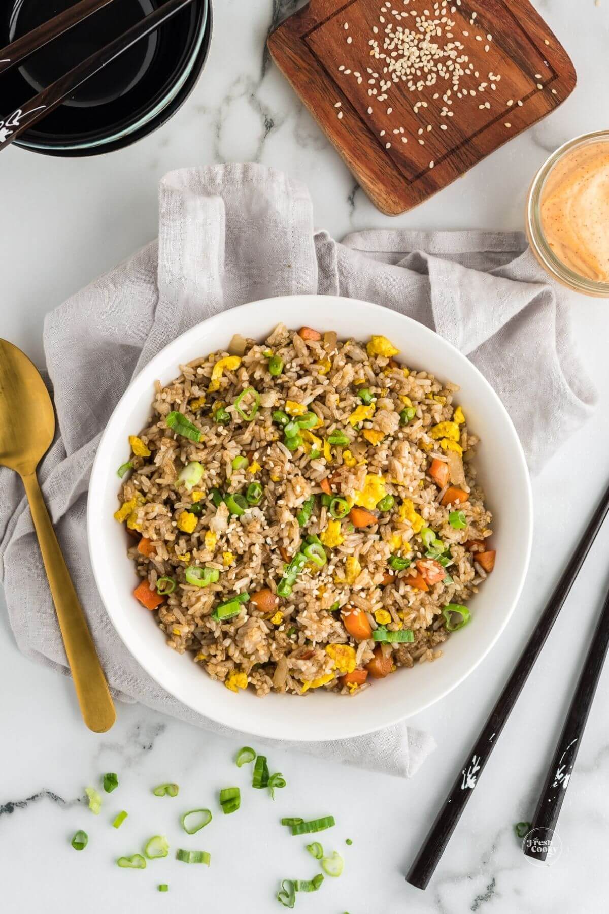 Large bowl full of Hibachi fried rice Benihana style with chopsticks and garnish.