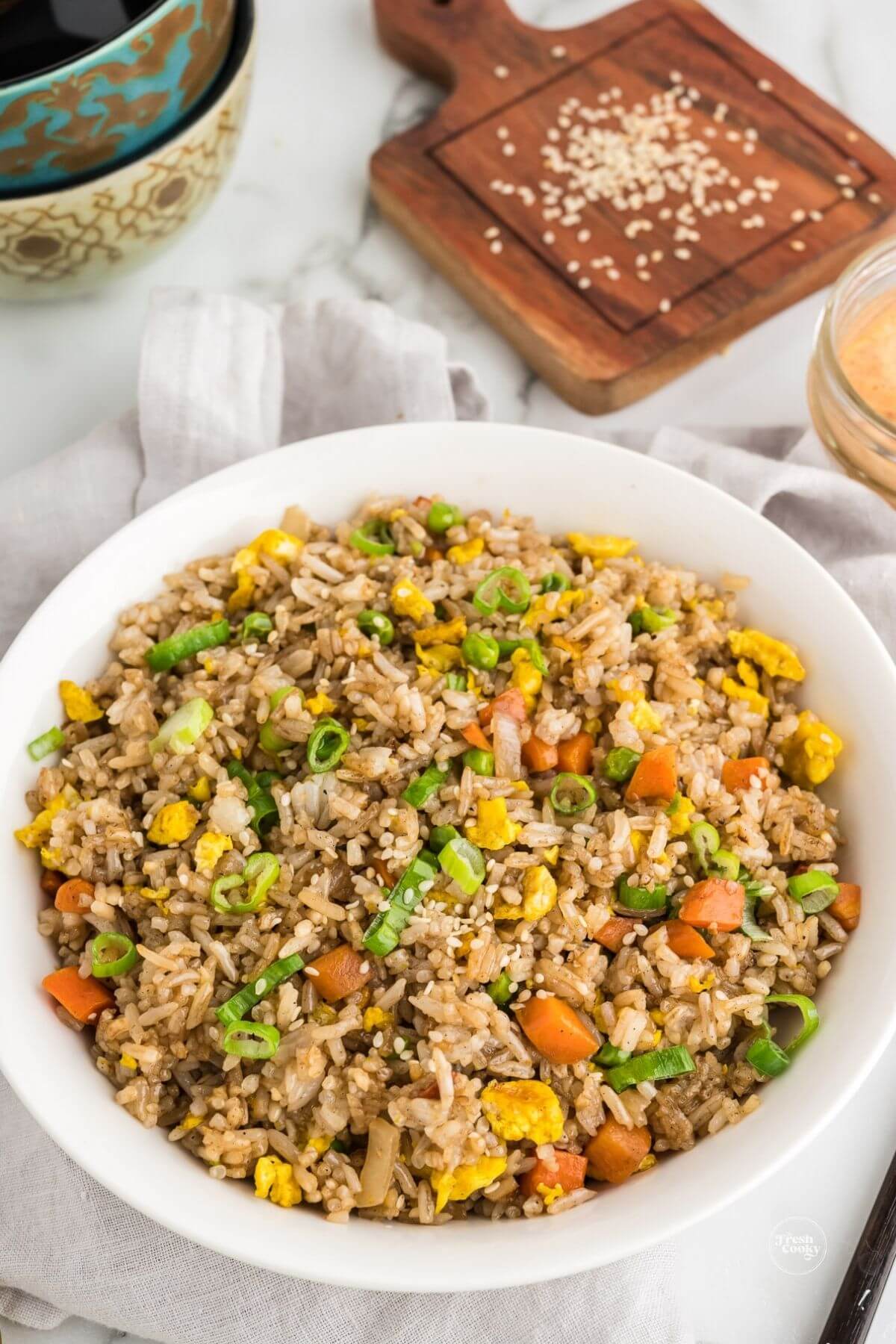 Bowl filled with hibachi fried rice with sesame seed garnish in background.