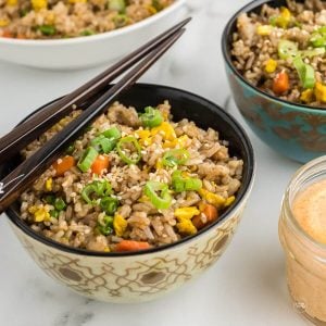 Bowls of Benihana style Hibachi fried rice with chopsticks and yum yum sauce.