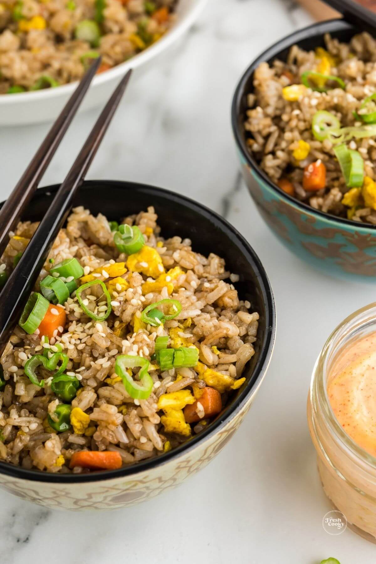 Benihana fried rice rice in bowls with chopsticks and yum yum sauce.