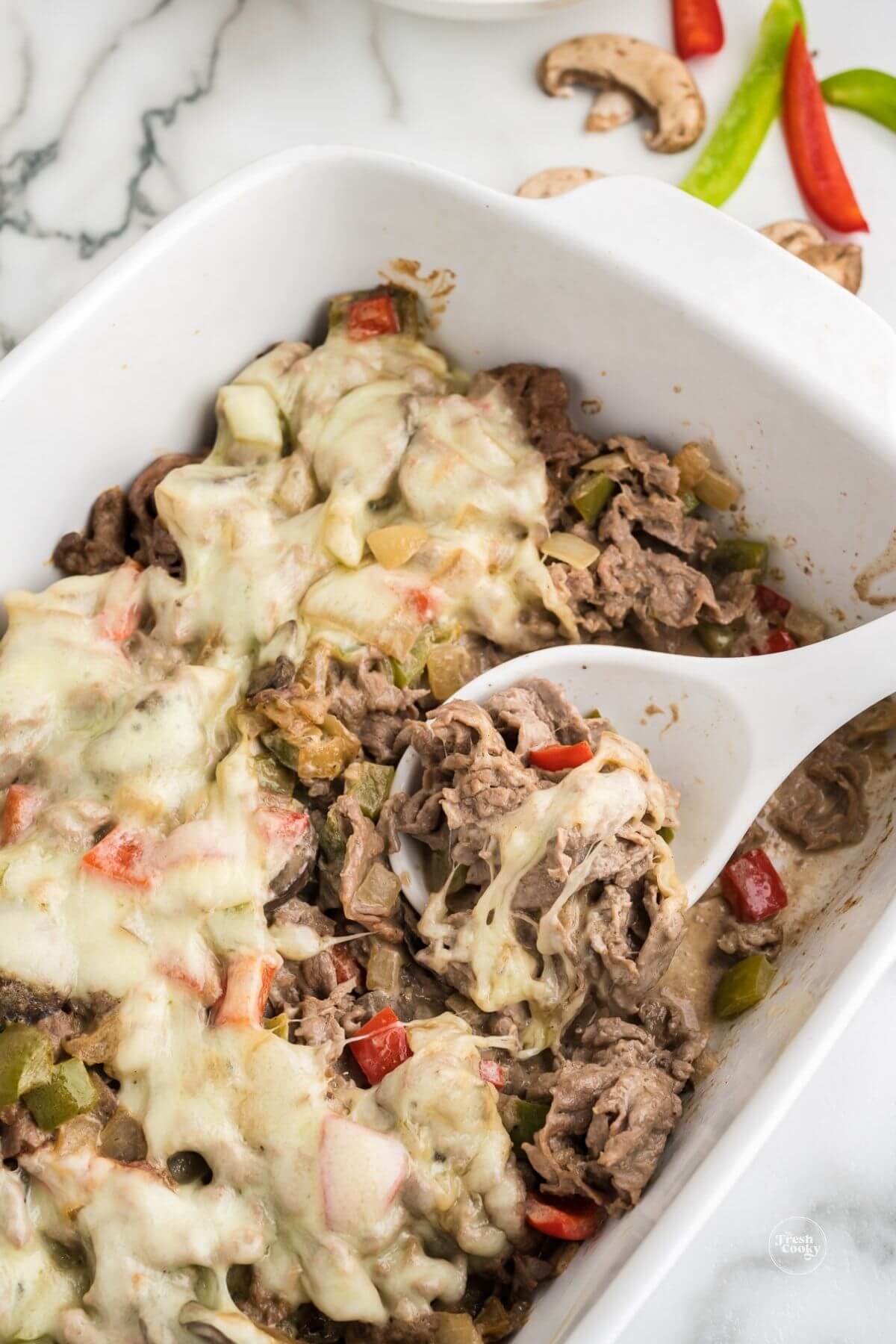 Spoon in casserole dish full of philly cheesesteak casserole recipe.