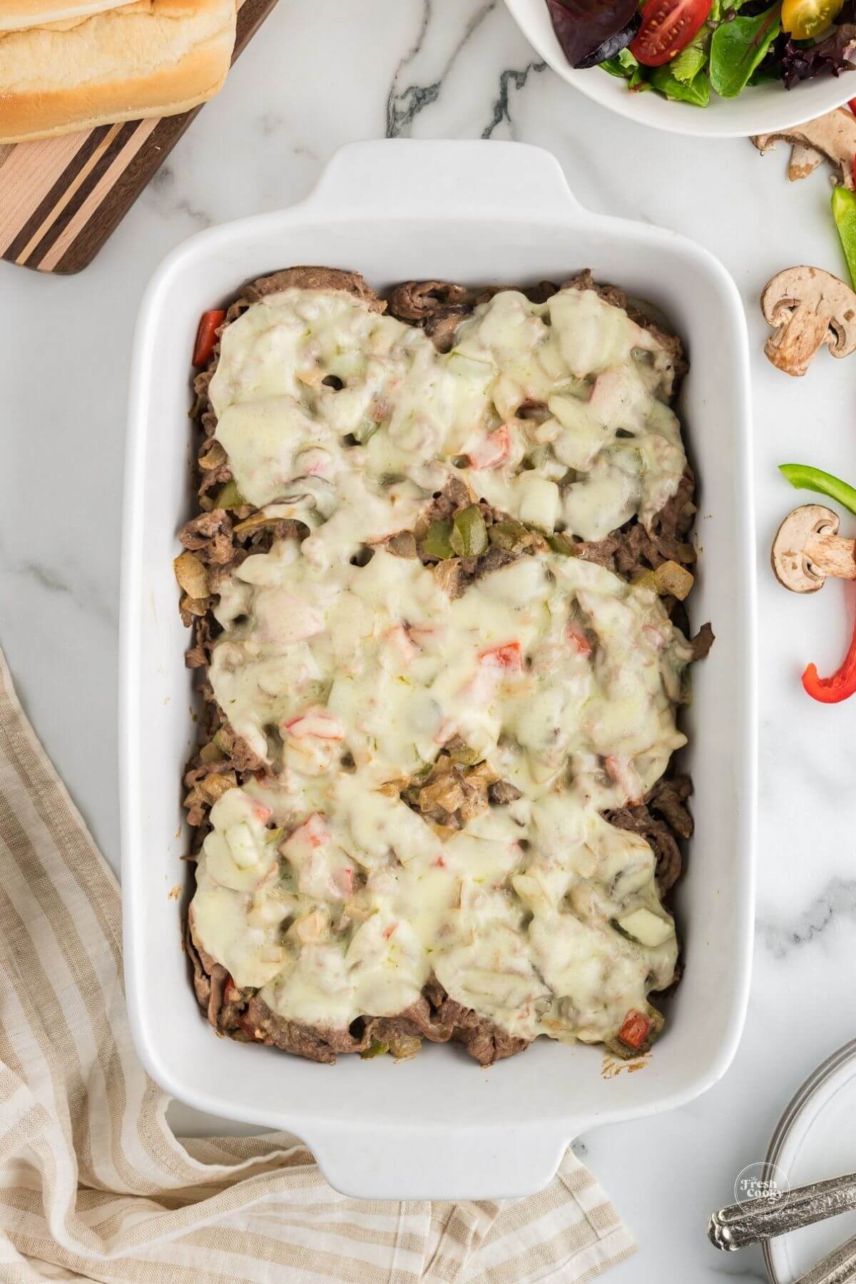 Easy low carb philly cheesesteak casserole in casserole dish, with melted cheese.