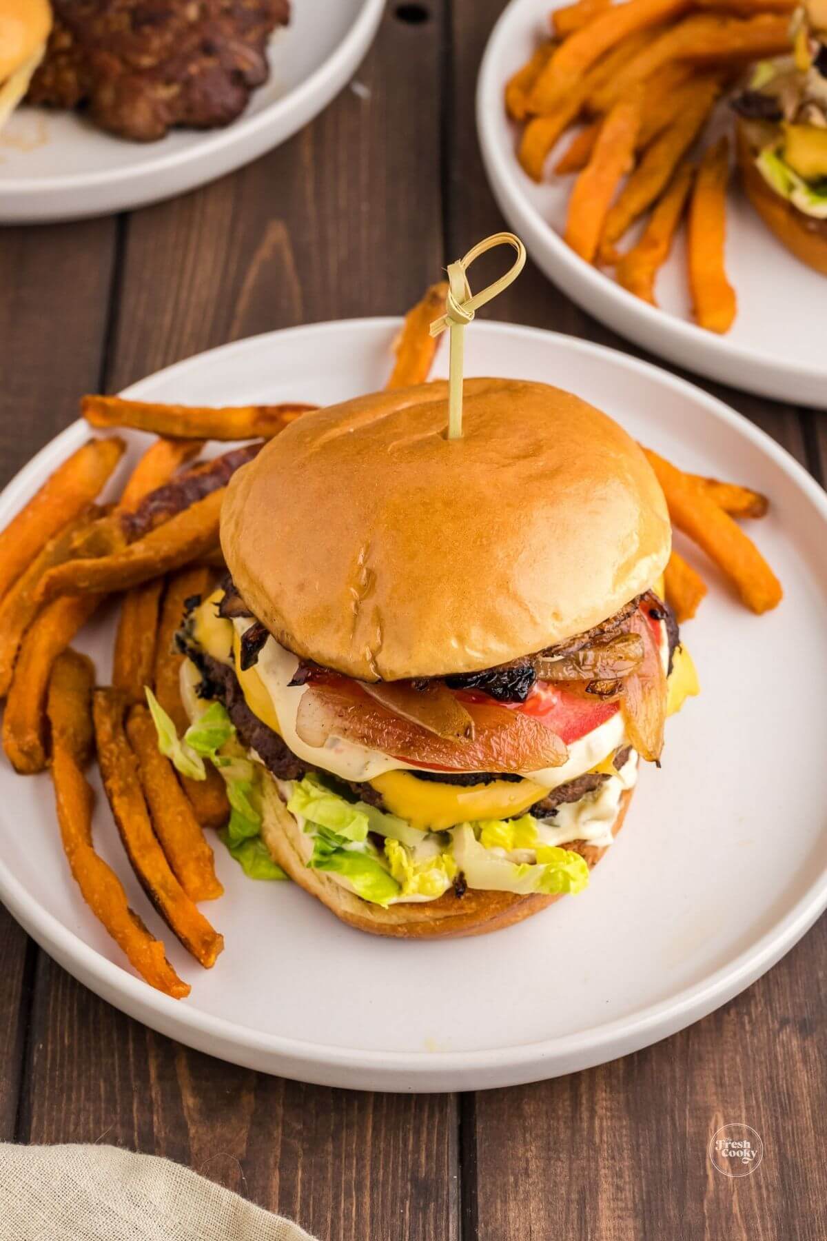 Smashburger on plate with sweet potato fries.