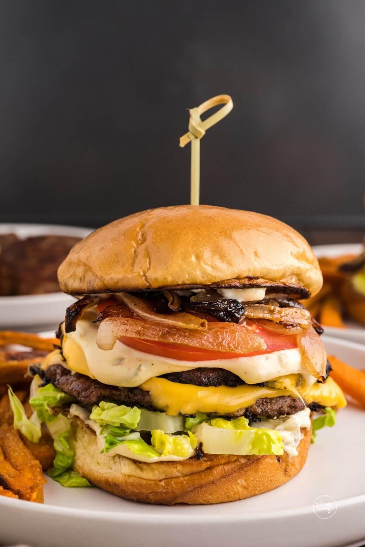 Best smashburger recipe blackstone burger on a plate, stacked high with toppings on a beautiful brioche bun.