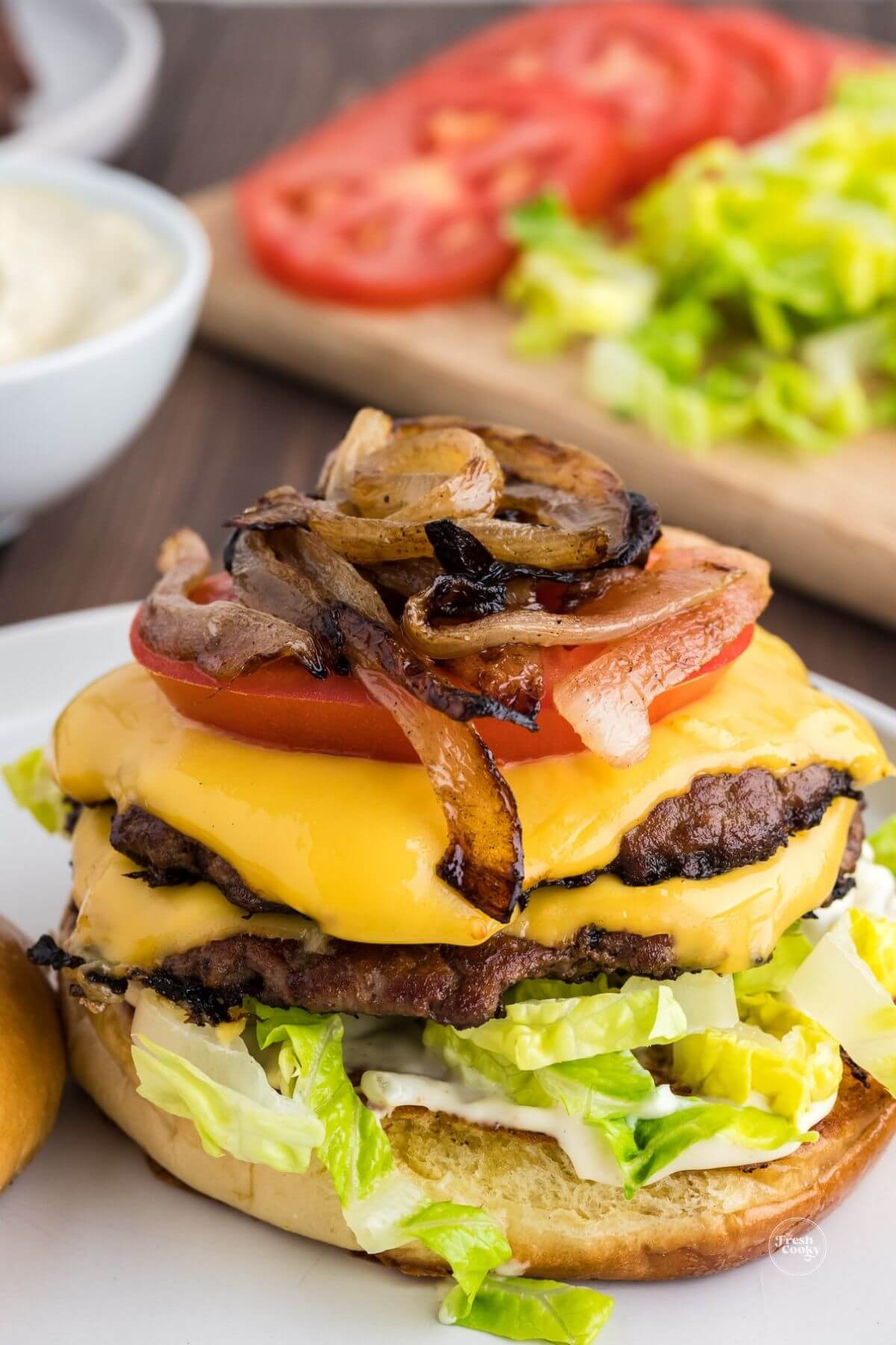 Layering a smashburger with lettuce, smash sauce,burgers, tomato and onions.