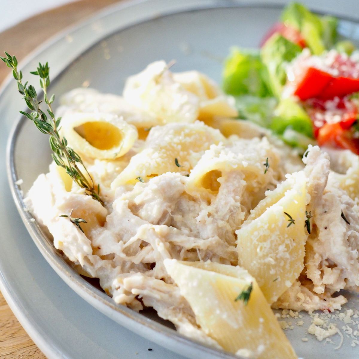 Olive Garden crockpot chicken with pasta on a plate with a green salad.