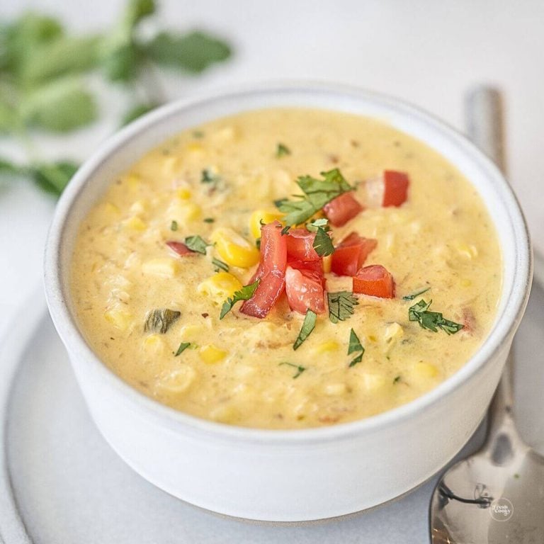 Panera bread summer corn chowder recipe, in a bowl topped with fresh tomatoes, onions and cilantro.