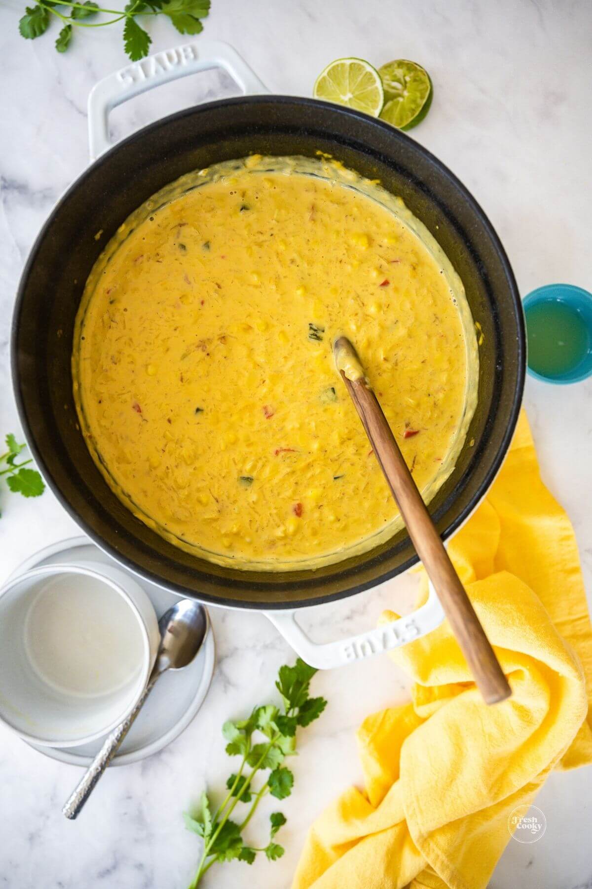 Dutch oven filled with fresh Summer Corn Chowder with wooden spoon for serving.