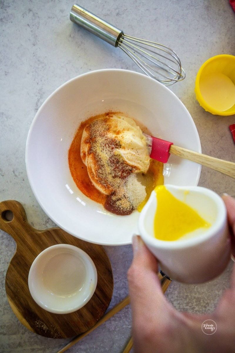 Adding melted butter to yum yum sauce.