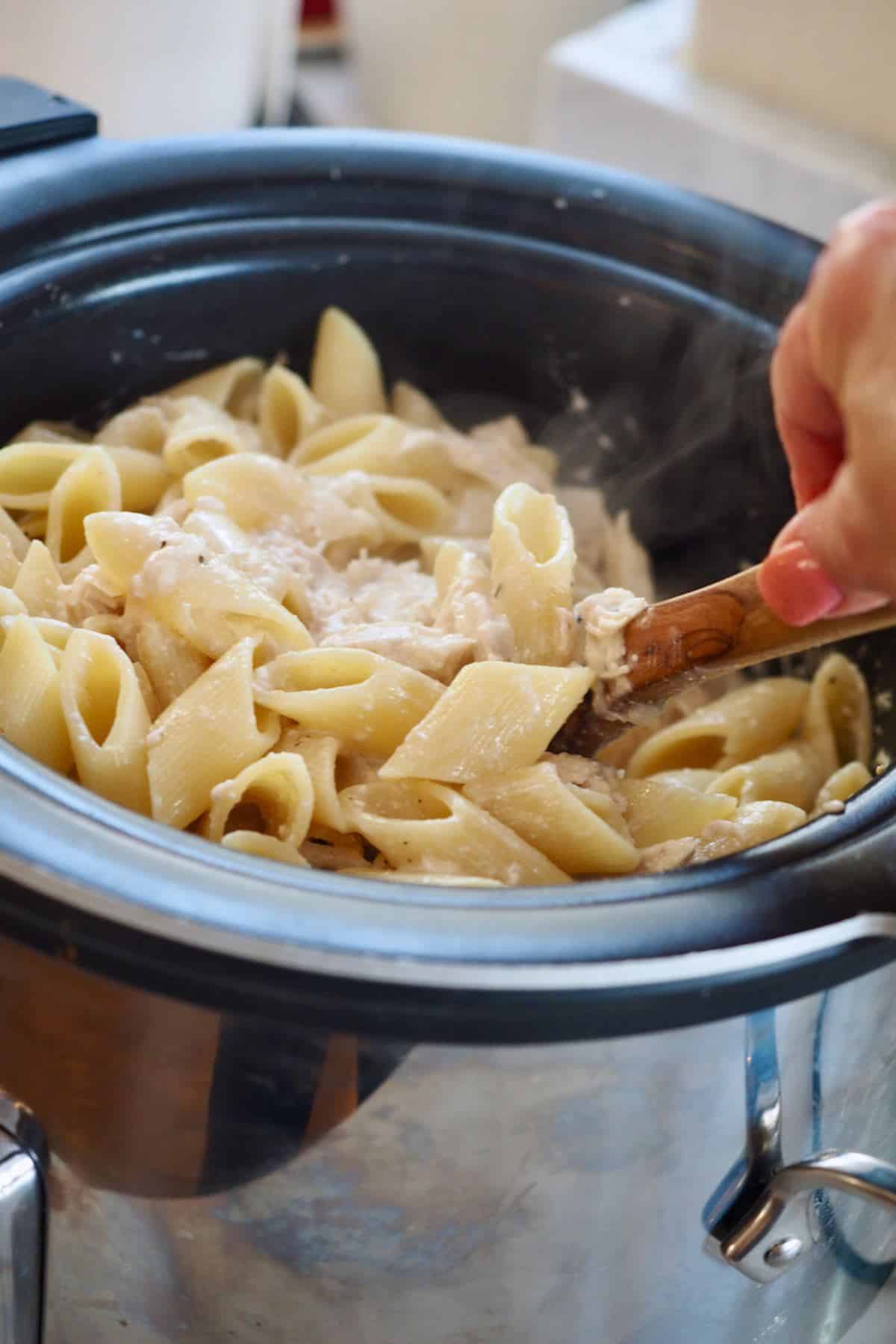 Hand stirring Olive Garden Chicken in crockpot.