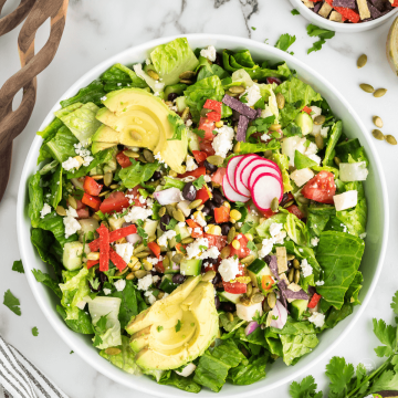 Easy Healthy Mexican Chopped Salad in large bowl with wooden serving tools nearby.