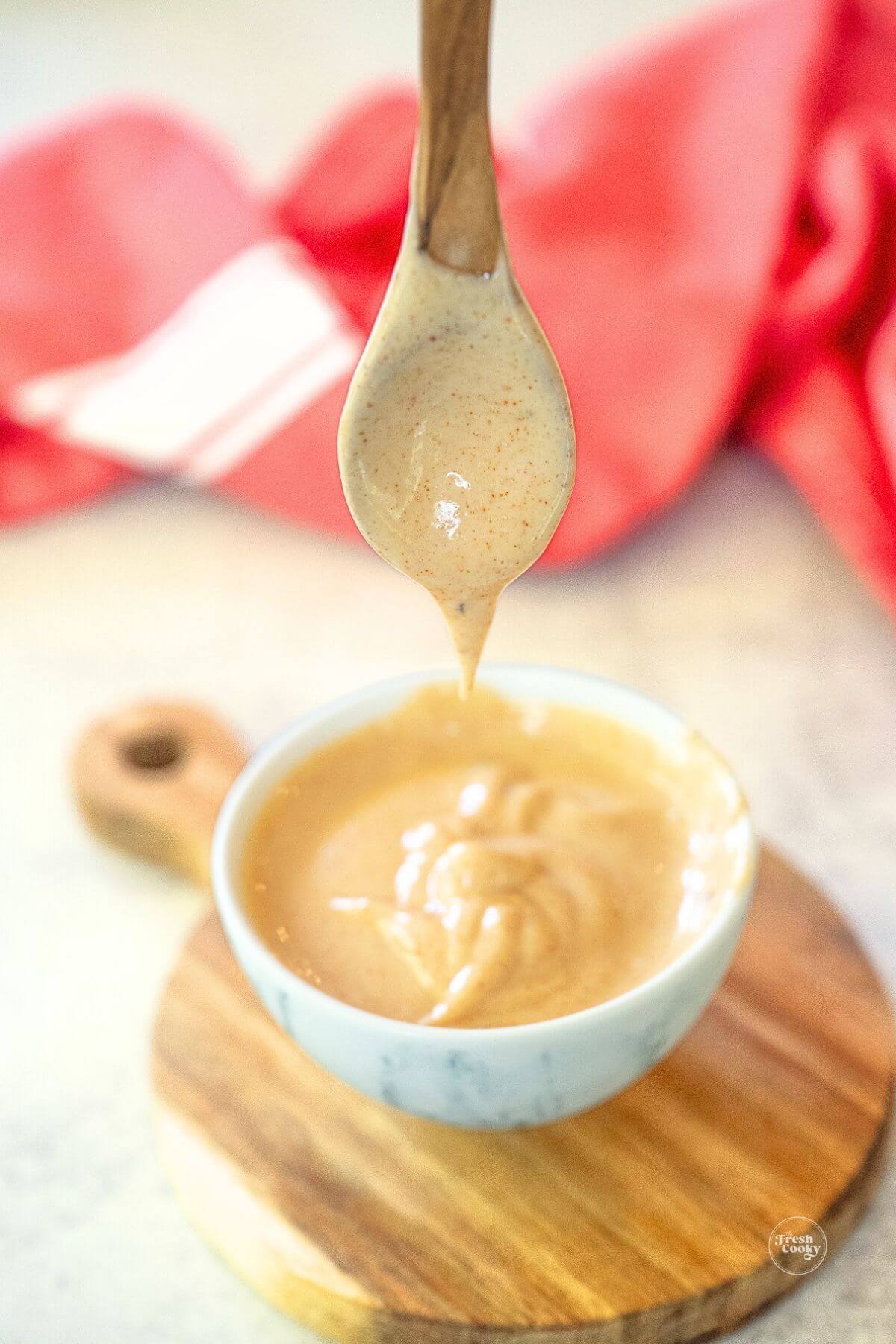 Dripping hibachi sauce from a wooden spoon into small bowl.