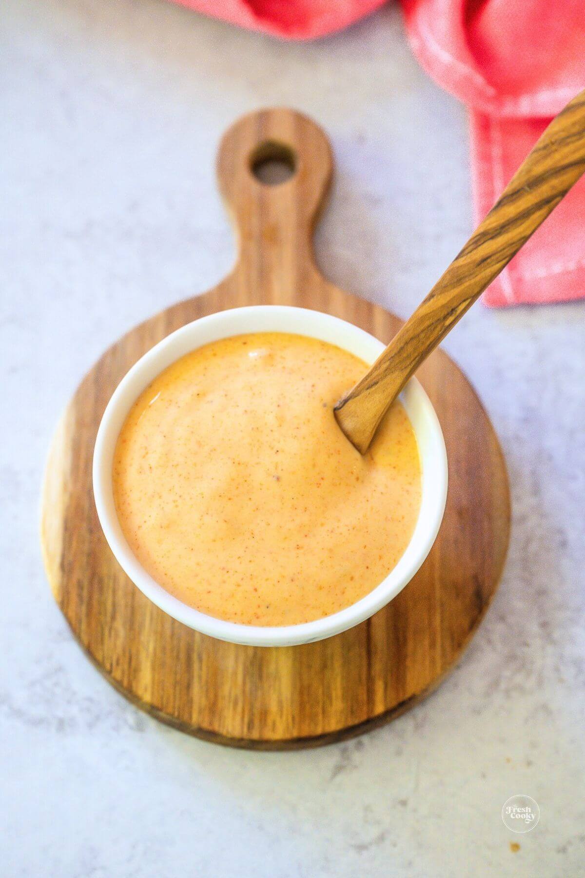 Yum Yum sauce in small bowl with wooden spoon.