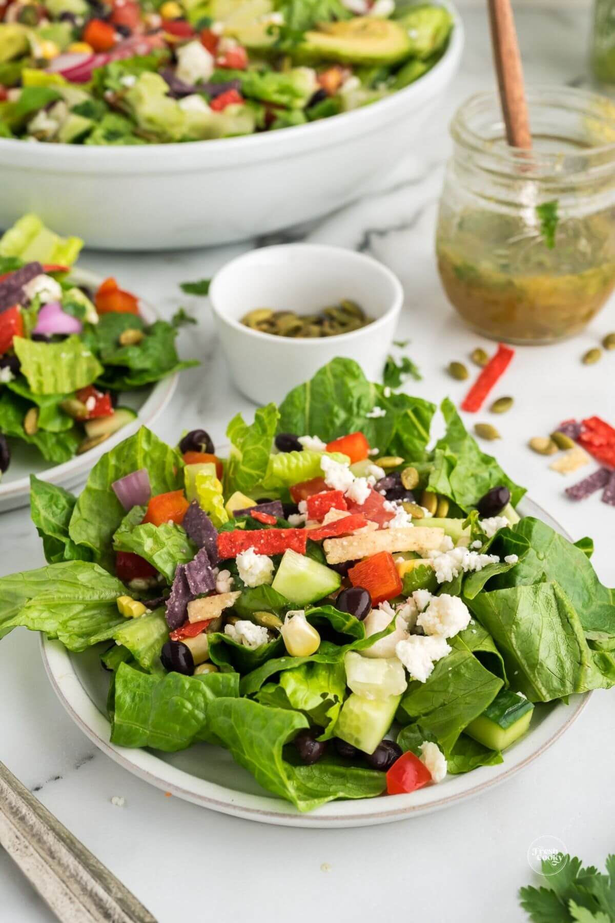 Easy Mexican chopped salad on a plate with fork and dressing behind.