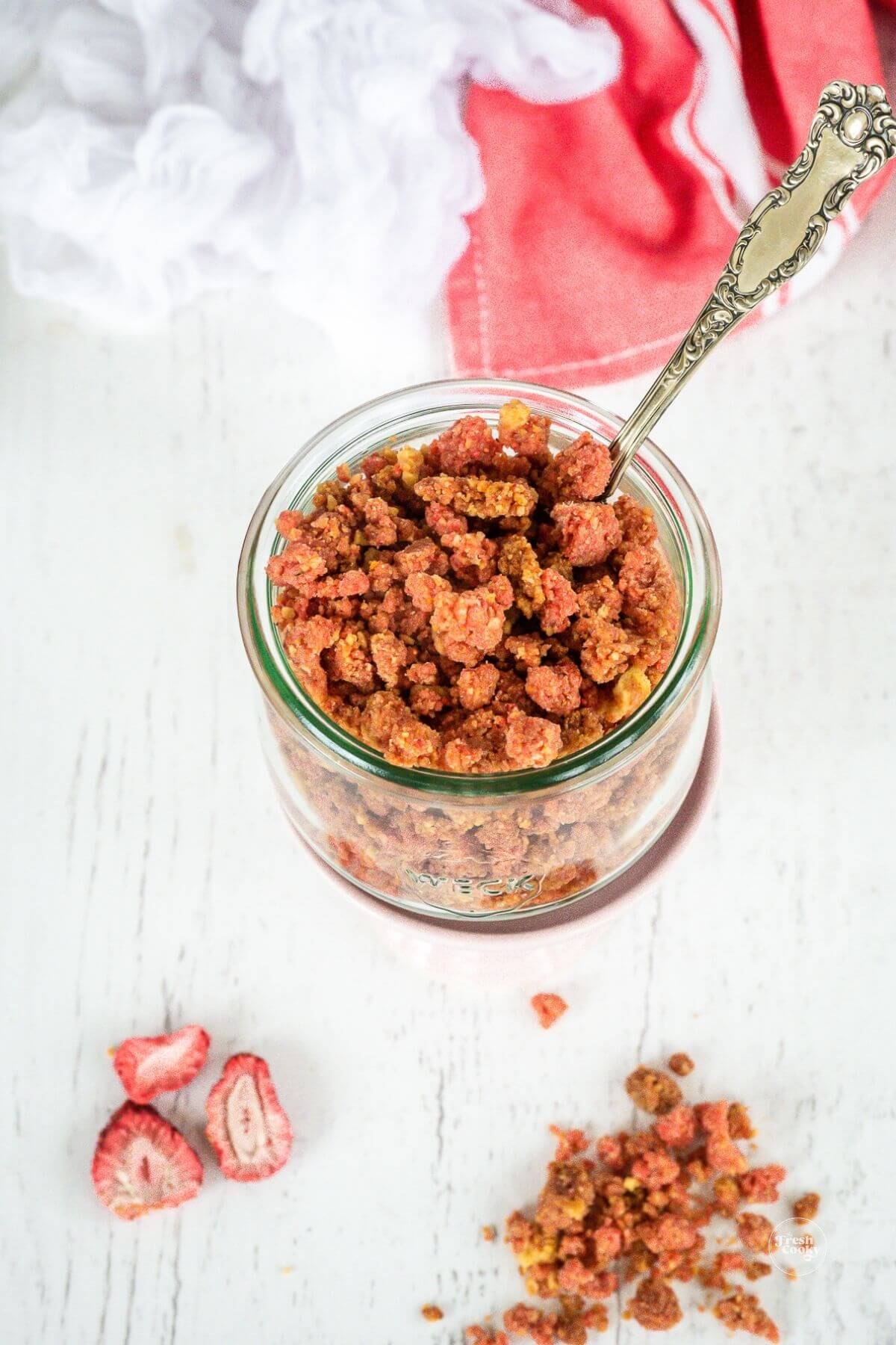 Strawberry crumble topping in jar with spoon.