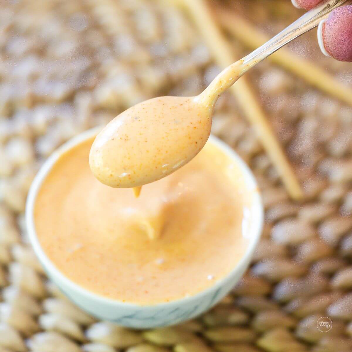 Yum yum sauce in small bowl with spoon holding the creamy hibachi sauce.