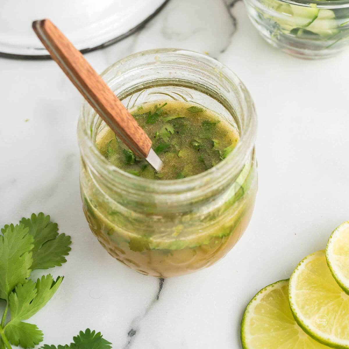 Jar of Cilantro Honey Lime Dressing with spoon for serving. 