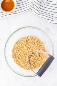 Pastry cutter in bowl mixing streusel crumb topping mixture for apple pies.