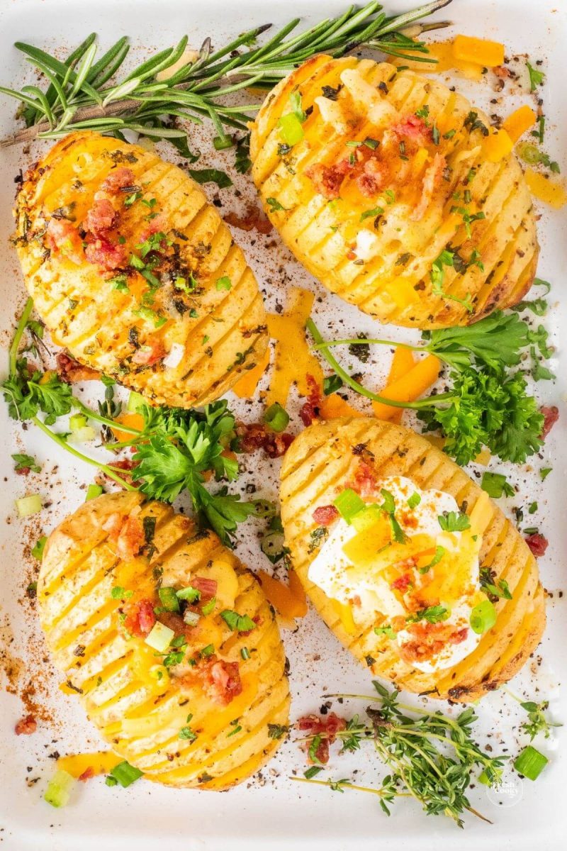 Air Fryer Hasselback potatoes with herbs on serving plate. 