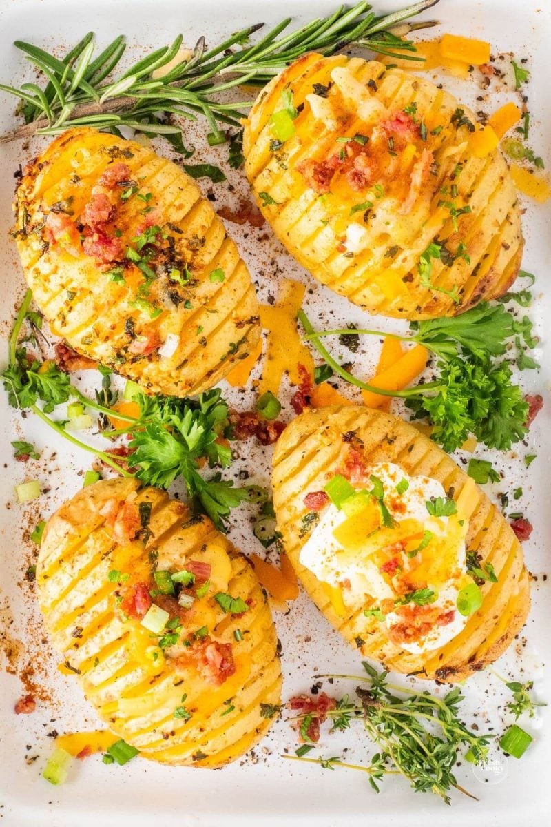 Air Fryer Hasselback potatoes with herbs on serving plate.