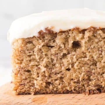 Best ever banana cake recipe on serving spatula, topped with cream cheese frosting.