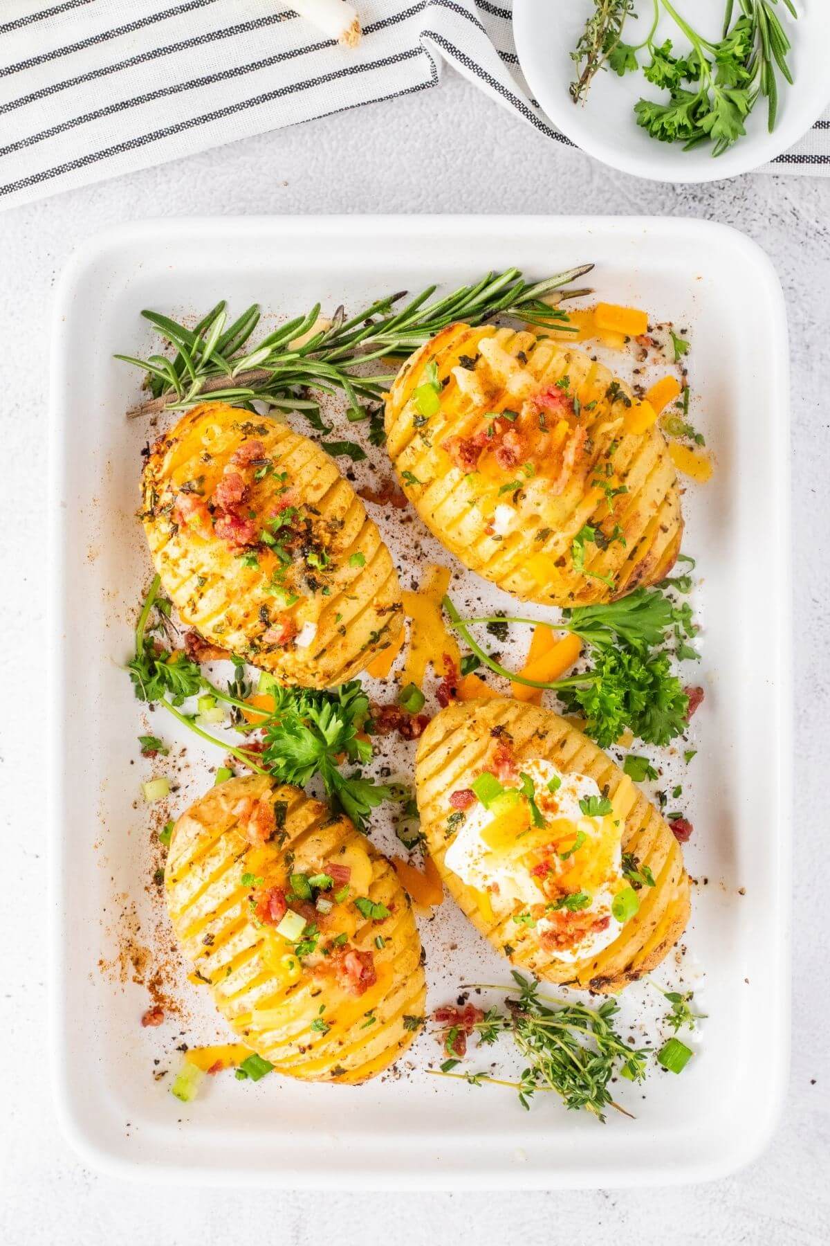 Hasselback potatoes with herbs and butter on a plate.