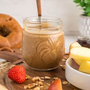 Granola butter in pretty jar with strawberries, apples and bagels.