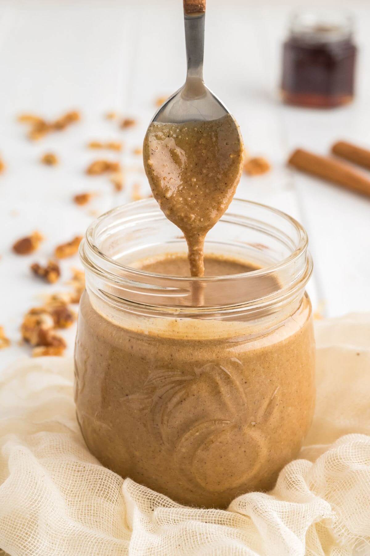 Granola butter, oat butter in jar with spoon drizzling.