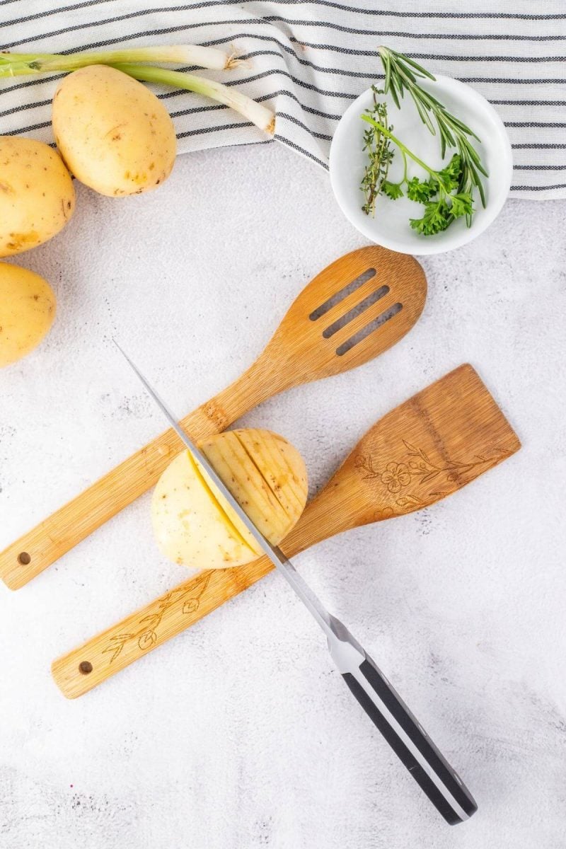Slicing hasselback potatoes using a guide.