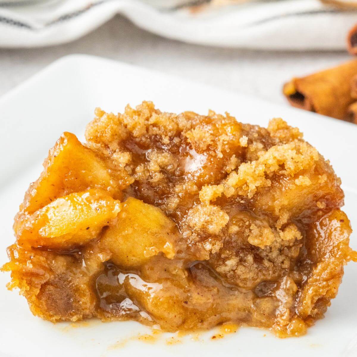 Mini apple pie on a plate with streusel topping and drizzle of caramel.
