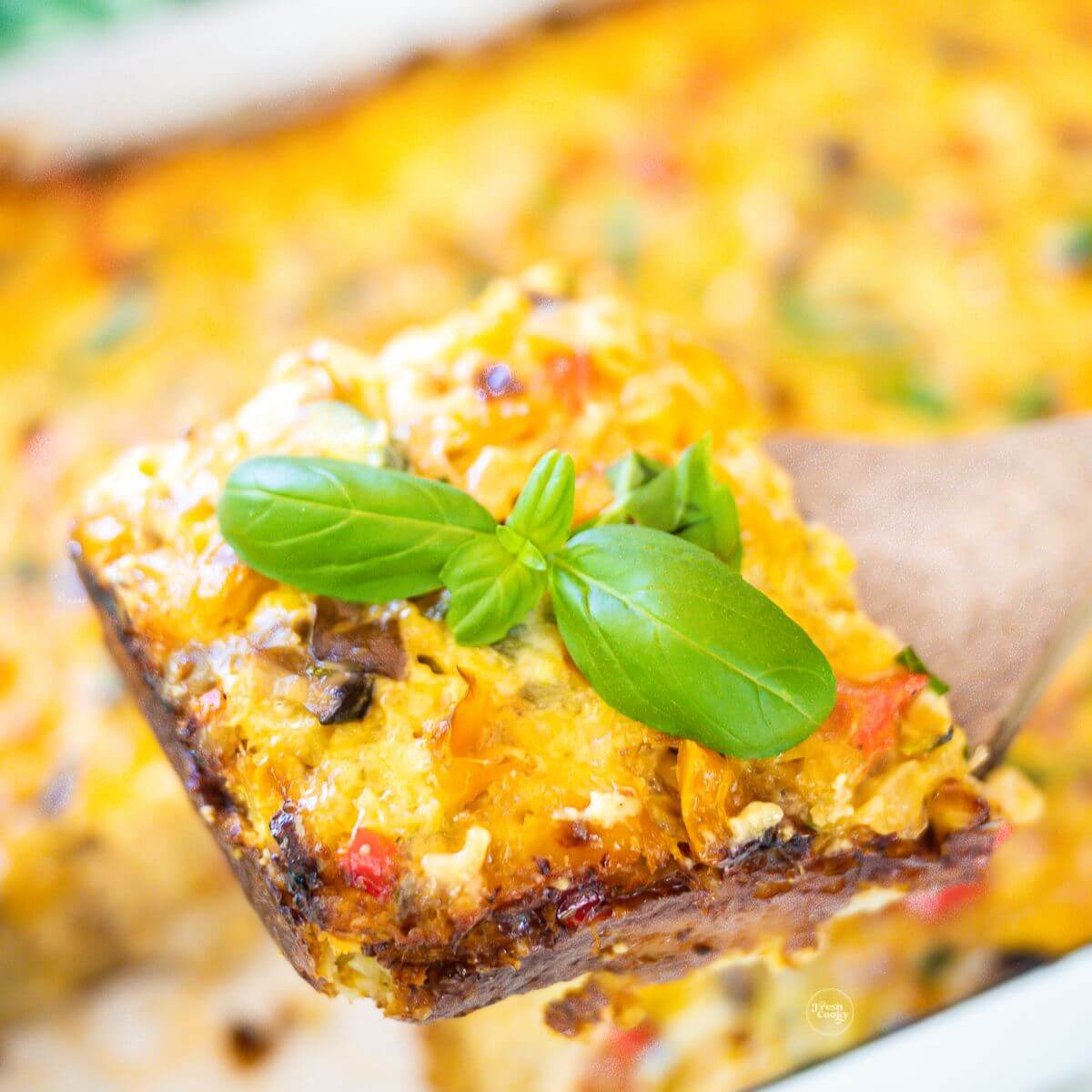 Vegetarian tater tot breakfast casserole with slice on a wooden server.