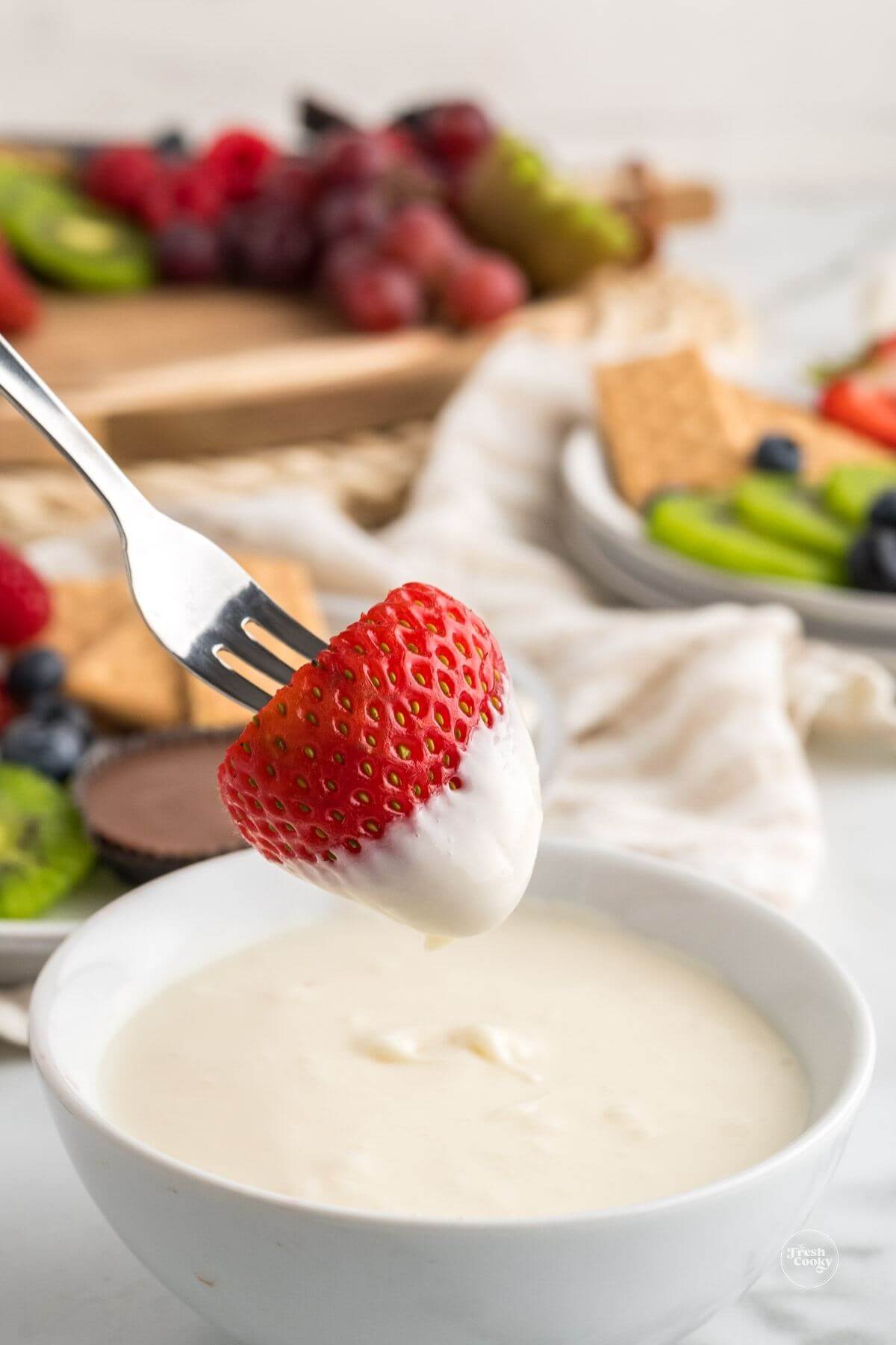 Strawberry on fork dipped into marshmallow fruit dip.