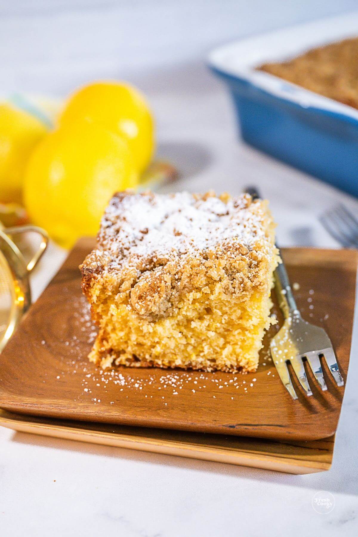 Slice of lemon crunch coffee cake topped with sprinkle of powdered sugar. 